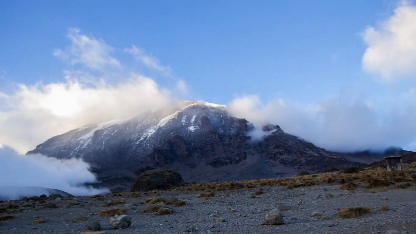 The snow-capped summit of Mount Kilimanjaro emerging from cloud